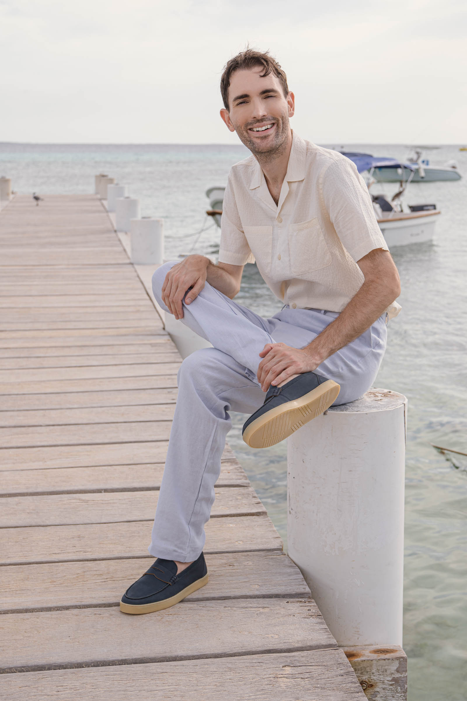 Marko Tadic blogger demonstrates minimalist elegance of Jil Sander brand wearing beige silk-cotton blend shirt, baby blue wide-leg linen trousers and blue suede loafers on exotic Los Roques destination