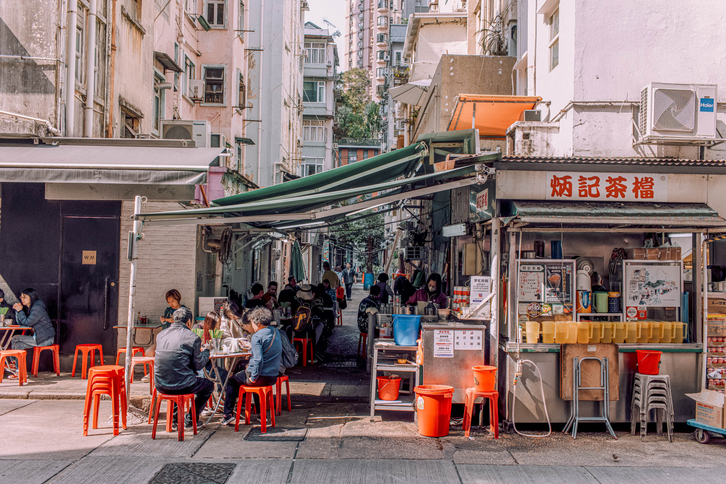 Nighttime Hong Kong street with traditional Chinese signage – A bustling side street glows with neon signs like “記茶檔” (tea stall) in Chinese characters amid modern high-rises, illustrating the city that never sleeps where old-world tea shops coexist with contemporary buildings (Hong Kong travel, street scene, neon Chinese signs, city night).