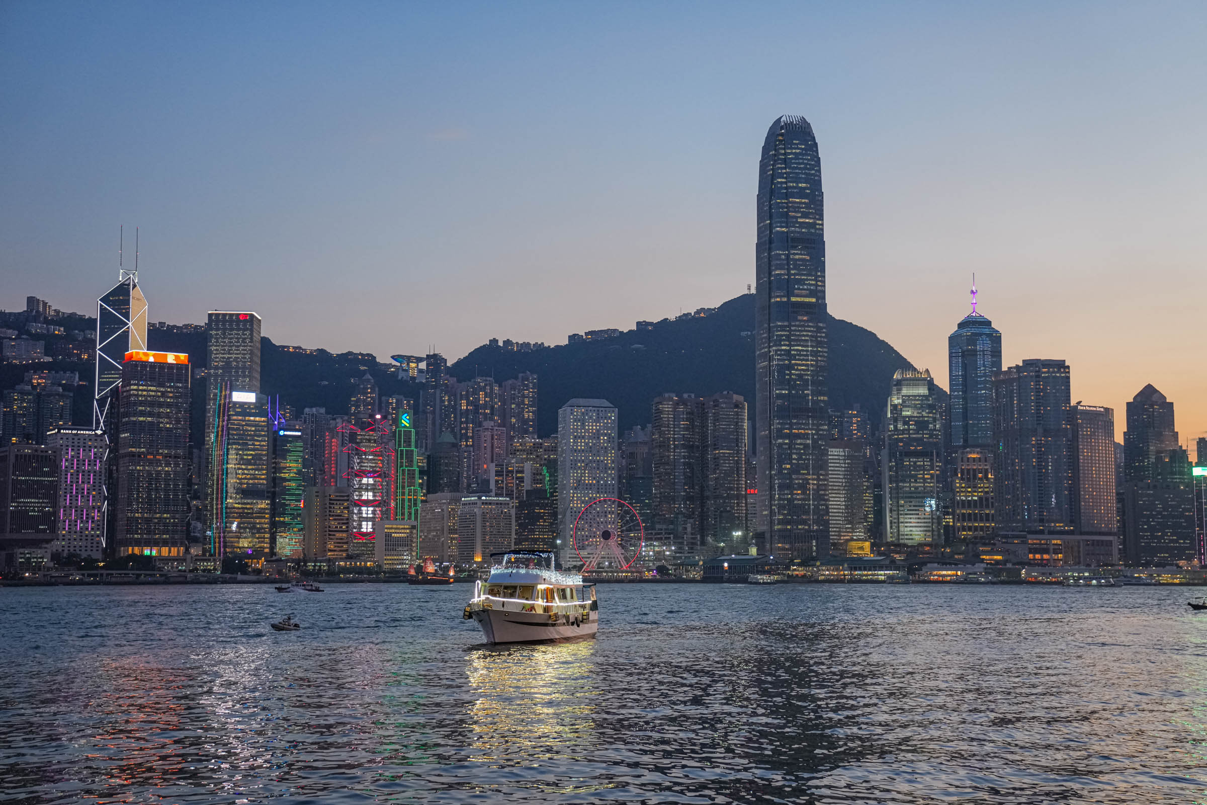 Hong Kong skyline at night during the Symphony of Lights – The skyscrapers along Victoria Harbour are illuminated in synchronized neon colors and laser beams that dance across the sky in the famous 8pm light show, their reflections shimmering on the water as crowds watch from the Tsim Sha Tsui promenade (Hong Kong travel, Symphony of Lights, skyline lights, night panorama).