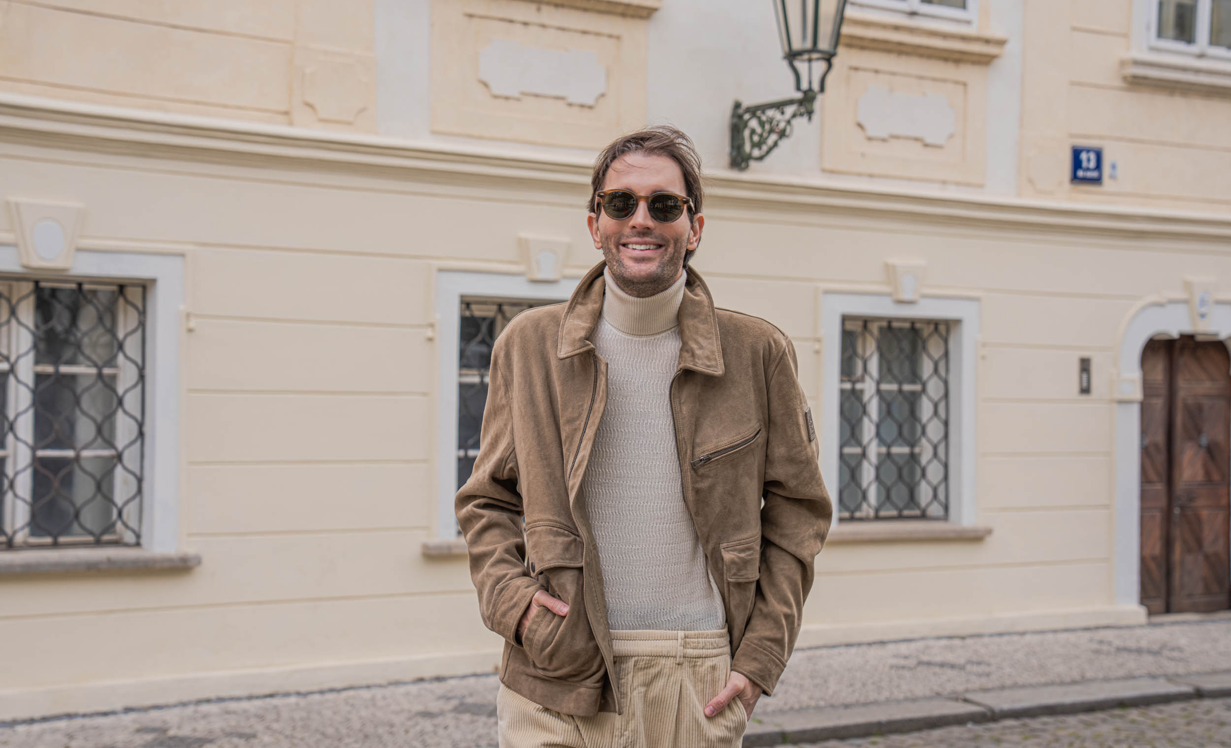 Marko Tadić, founder of Mr.M by Marko Tadić blog, walking toward camera with hands in pockets in a tonal beige spring outfit by Belstaff, Armani and Loro Piana.