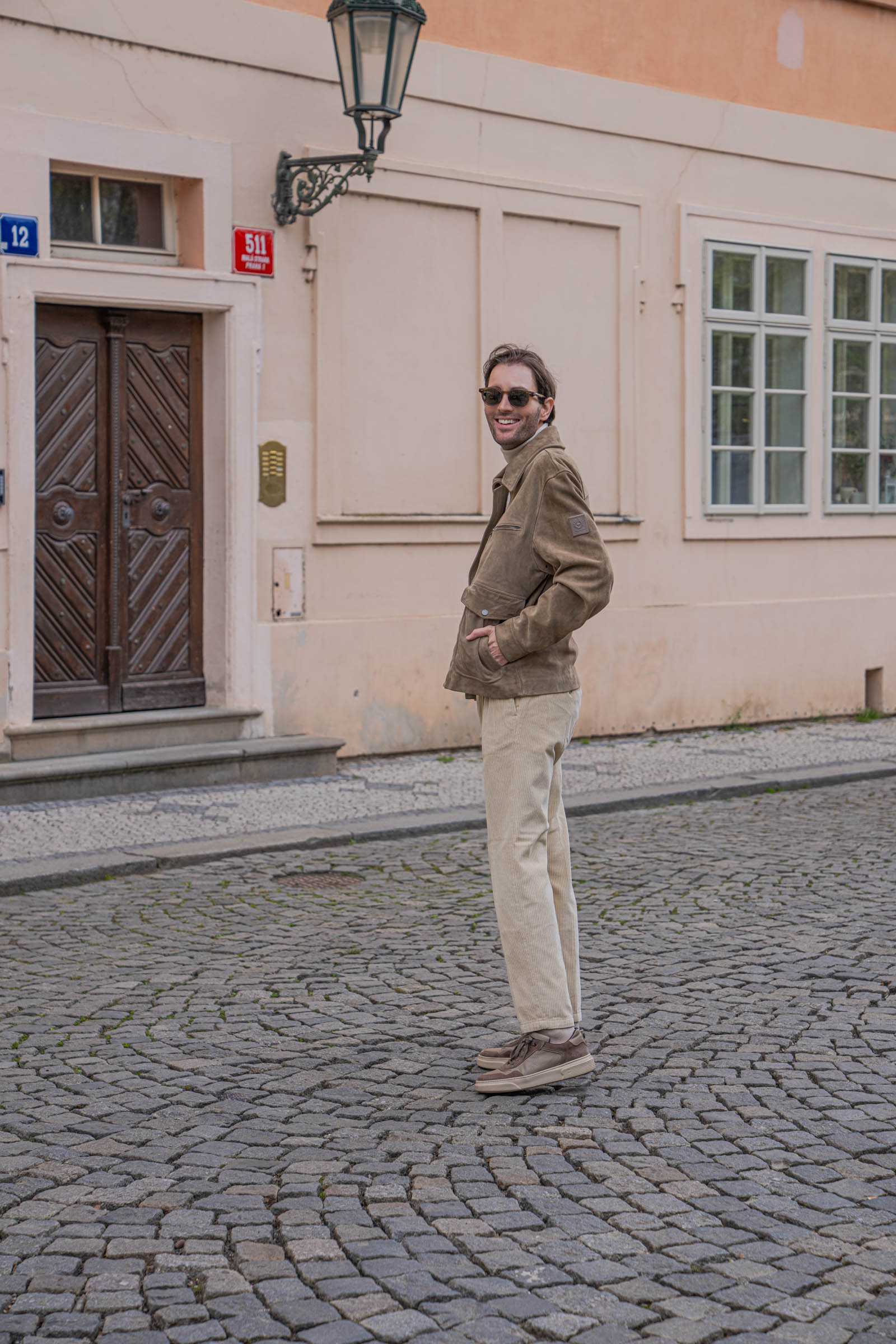 Marko Tadić, founder of Mr.M by Marko Tadić blog, smiling three-quarter portrait showing the textured Armani cashmere turtleneck under a Belstaff suede aviator jacket.