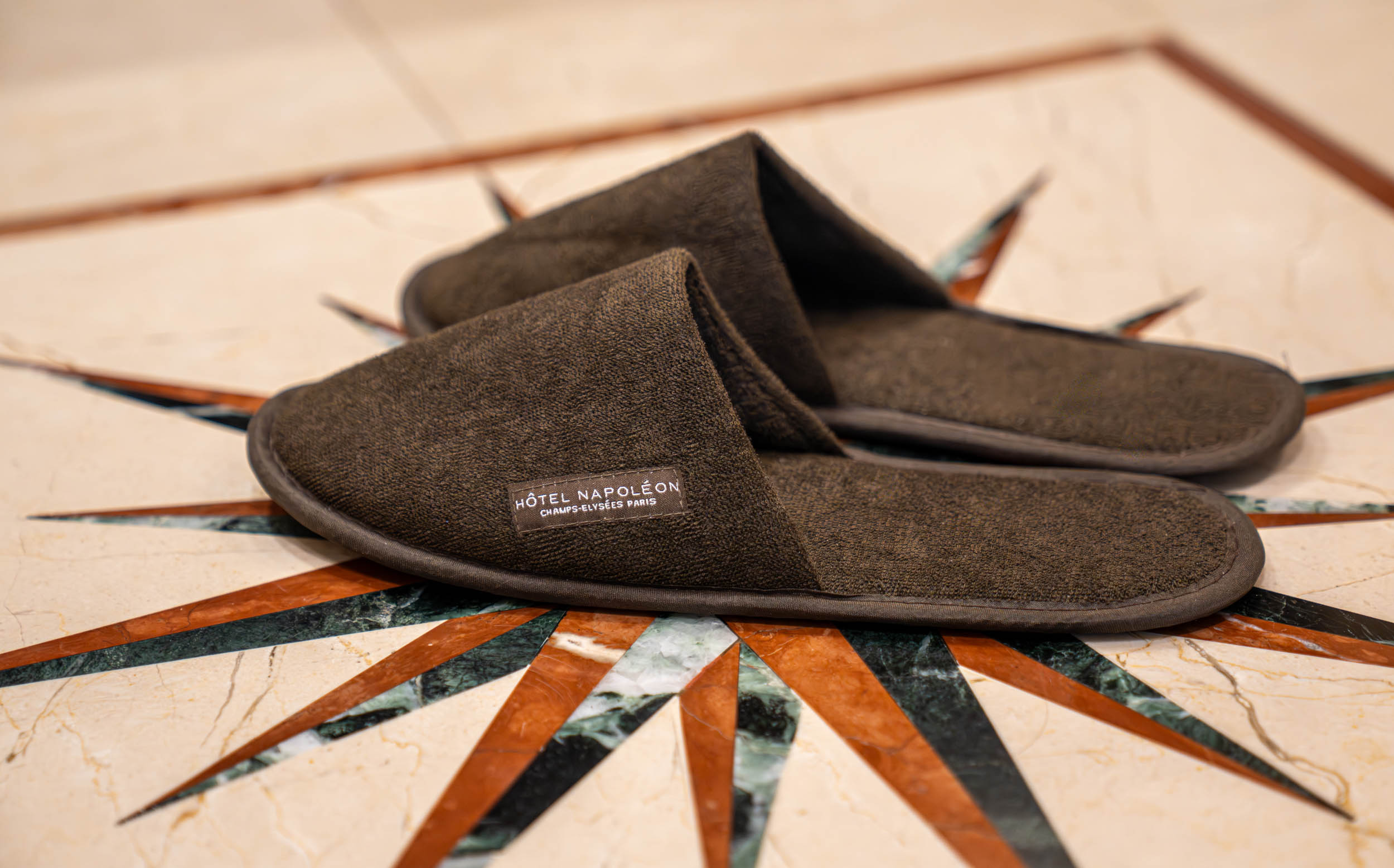 Soft brown Hôtel Napoléon Champs-Élysées Paris terry slippers worn on a marble floor with a red silk robe, photo by Marko Tadić, founder of Mr.M by Marko Tadić blog