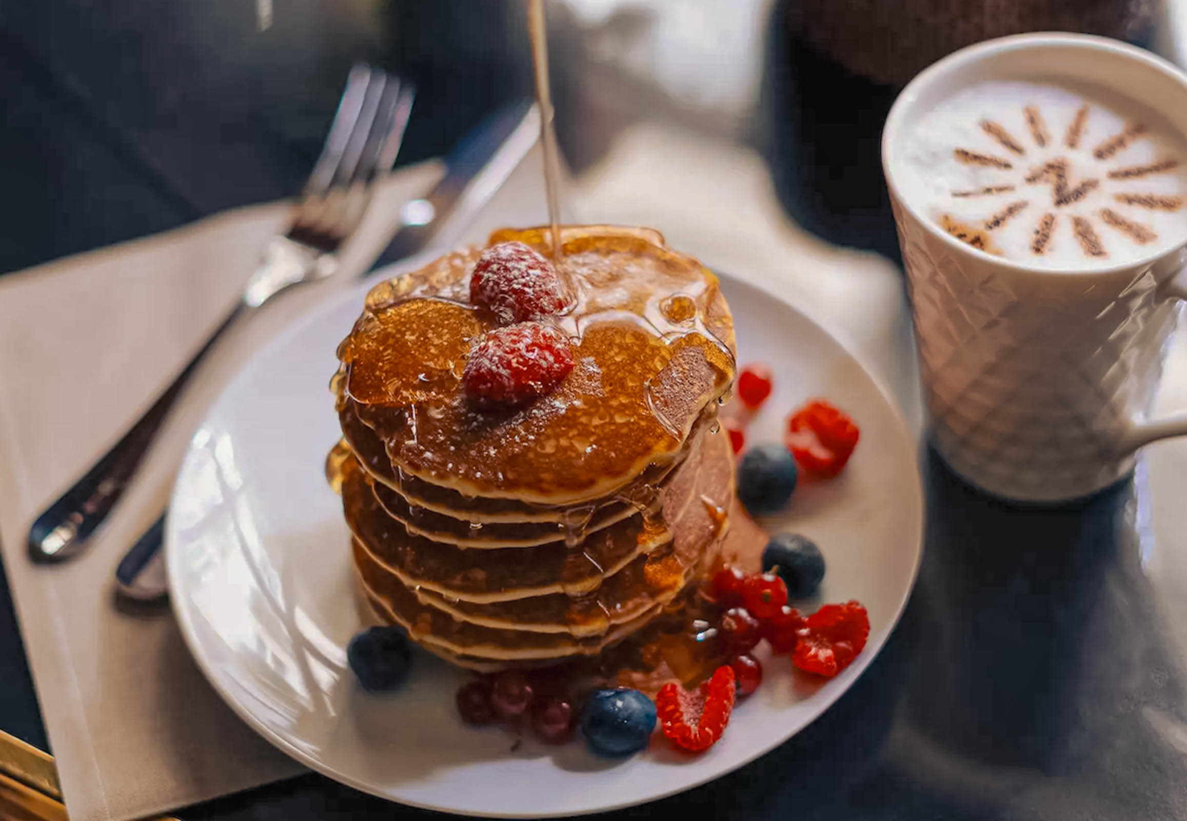 Stack of pancakes with syrup, fresh berries and a cappuccino with the Hôtel Napoléon Paris logo at breakfast, photo by Marko Tadić, founder of Mr.M by Marko Tadić blog