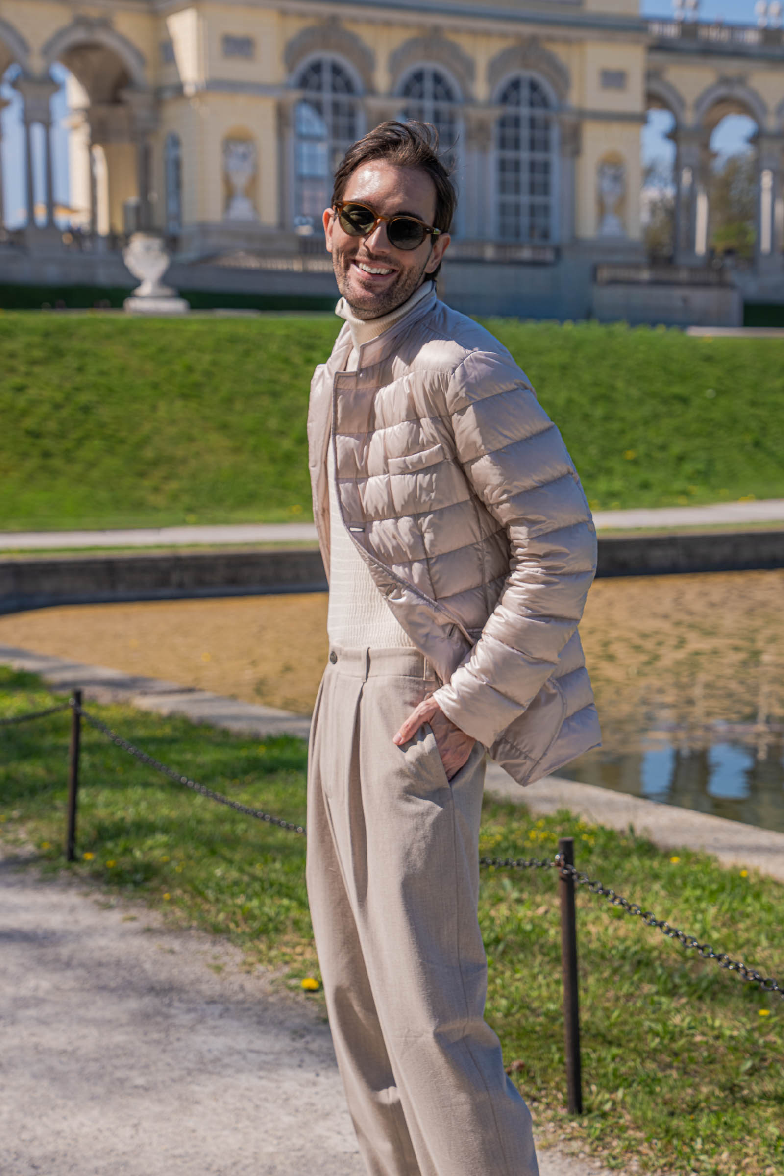 Marko Tadić, founder of the Mr.M blog, standing before the full Gloriette facade at Schönbrunn in a beige spring menswear look