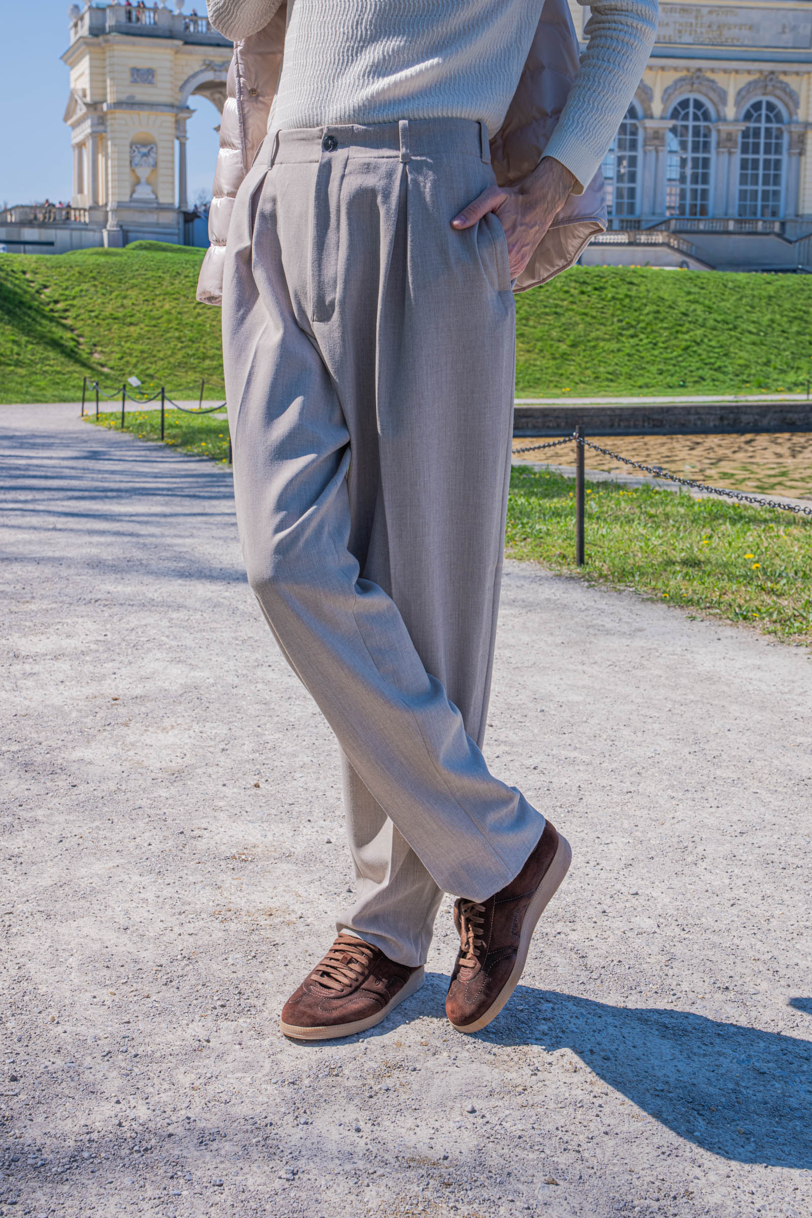 Detail of Giorgio Armani wide-leg beige trousers and Santoni Oly brown suede sneakers worn by Marko Tadić, founder of the Mr.M blog, in Vienna