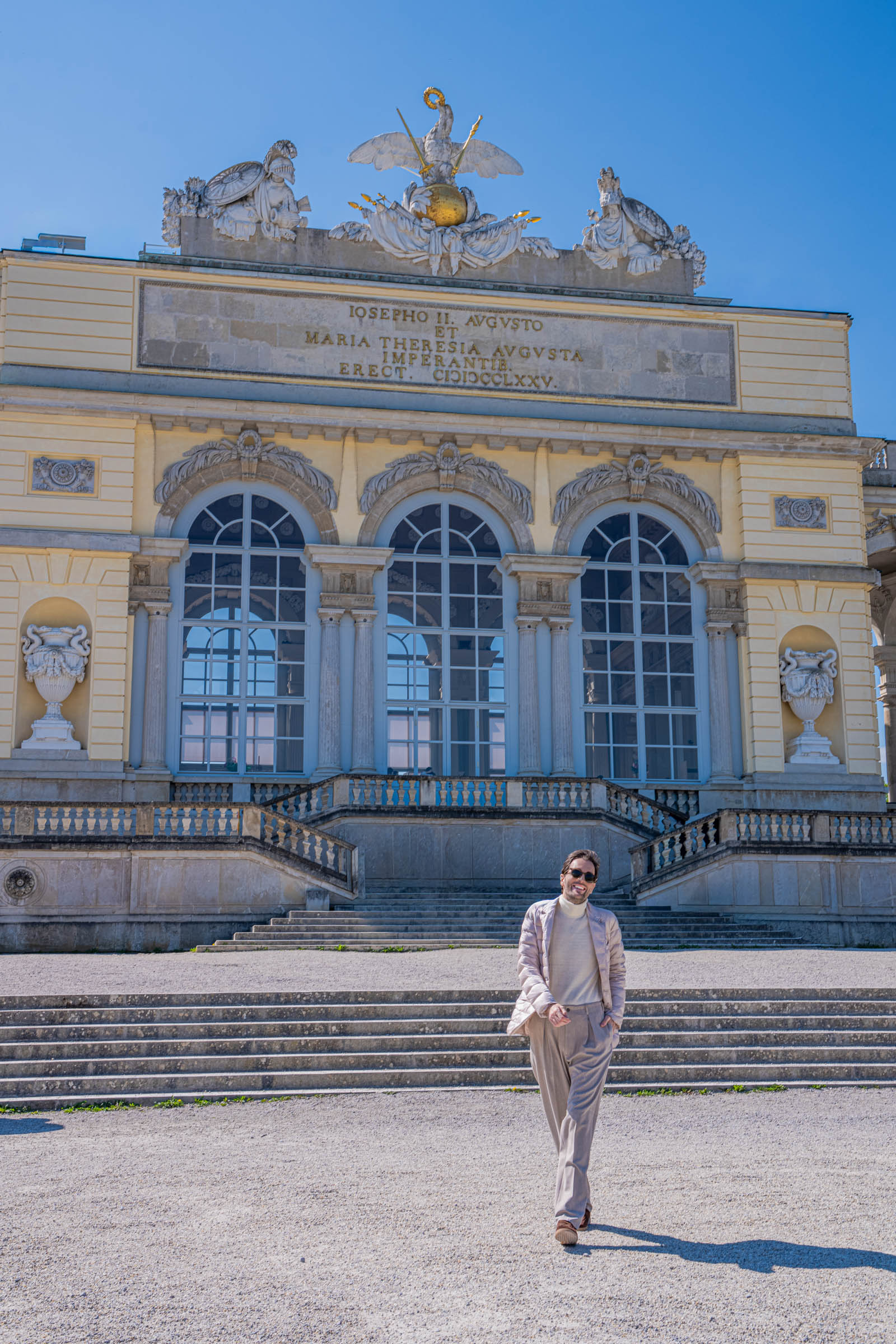 Marko Tadić, founder of the Mr.M blog, walking towards the camera in a full beige Giorgio Armani style outfit at the Schönbrunn Gloriette