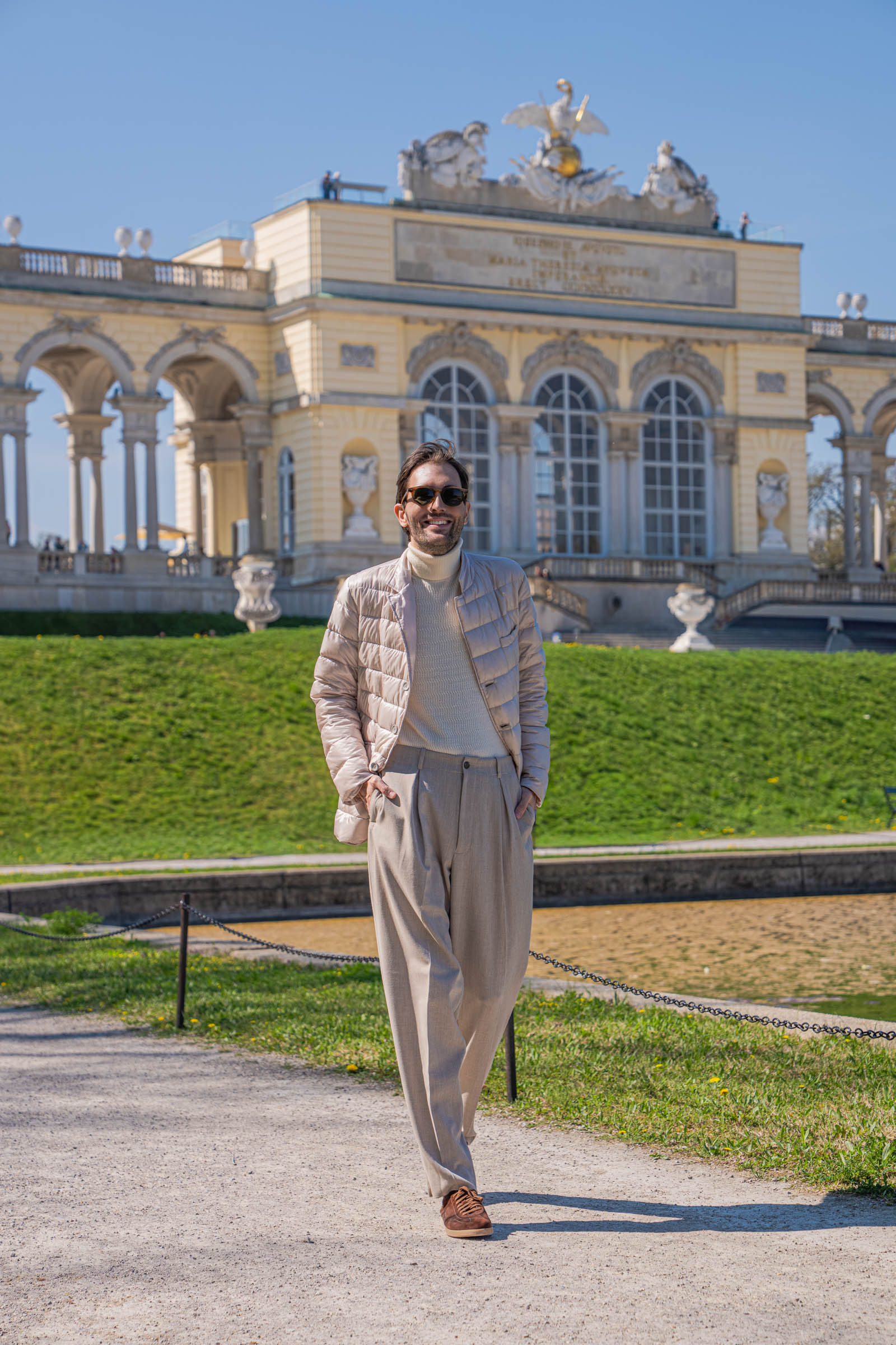 Marko Tadić, founder of the Mr.M blog, walking on the gravel path in Giorgio Armani style with the Schönbrunn Gloriette colonnade behind him