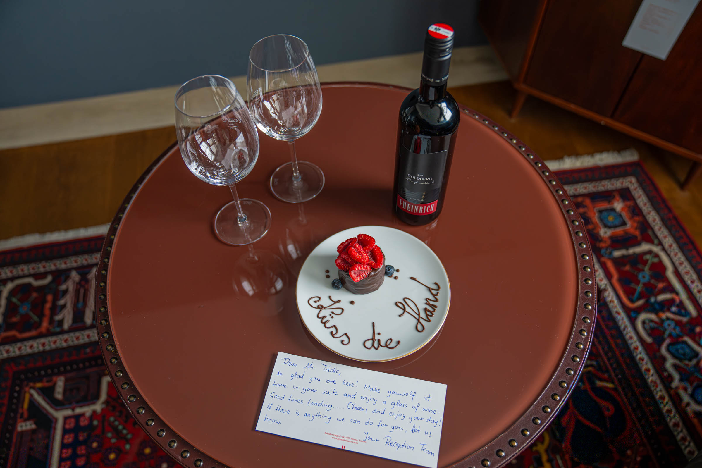 Welcome treat at Grand Ferdinand Vienna: Austrian red wine and chocolate cake with a handwritten Küss die Hand note