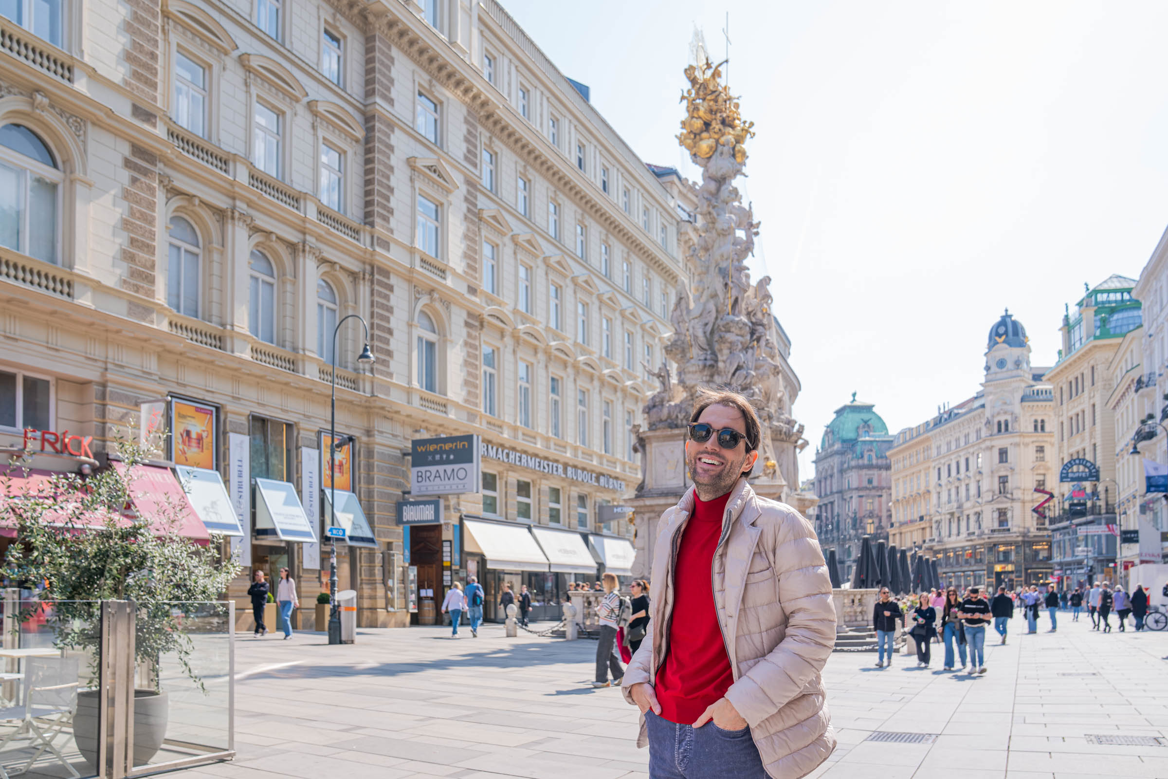 Travel blogger Marko Tadić smiling on Graben street in Vienna with the baroque Plague Column behind him