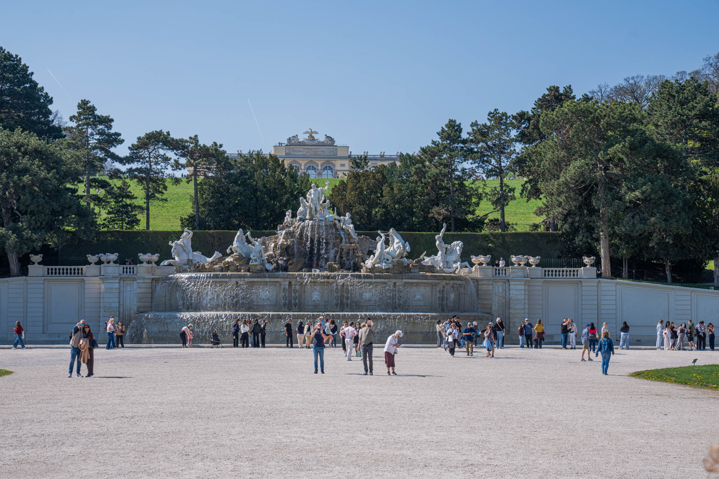Neptune Fountain at Schönbrunn Palace with cascading water and marble sculptures among the trees