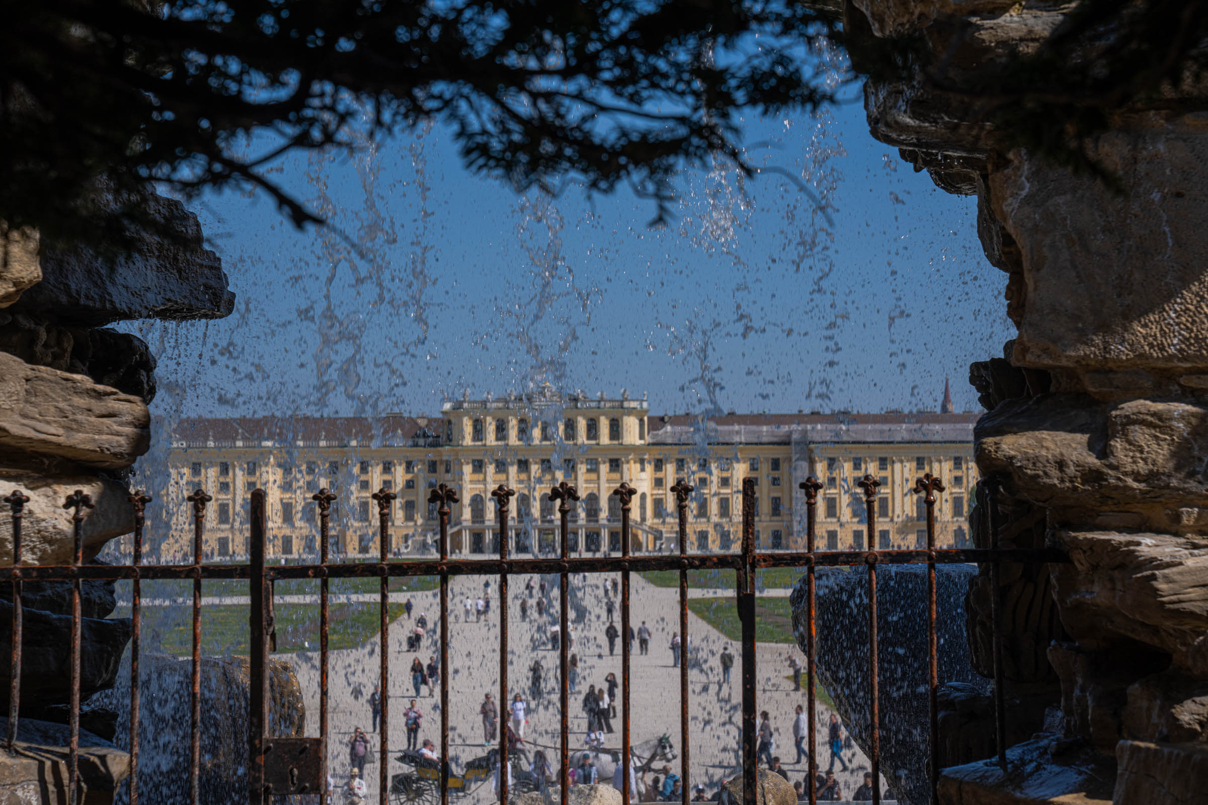Schönbrunn Palace seen through the falling water curtain of the Neptune Fountain, a magical Vienna view