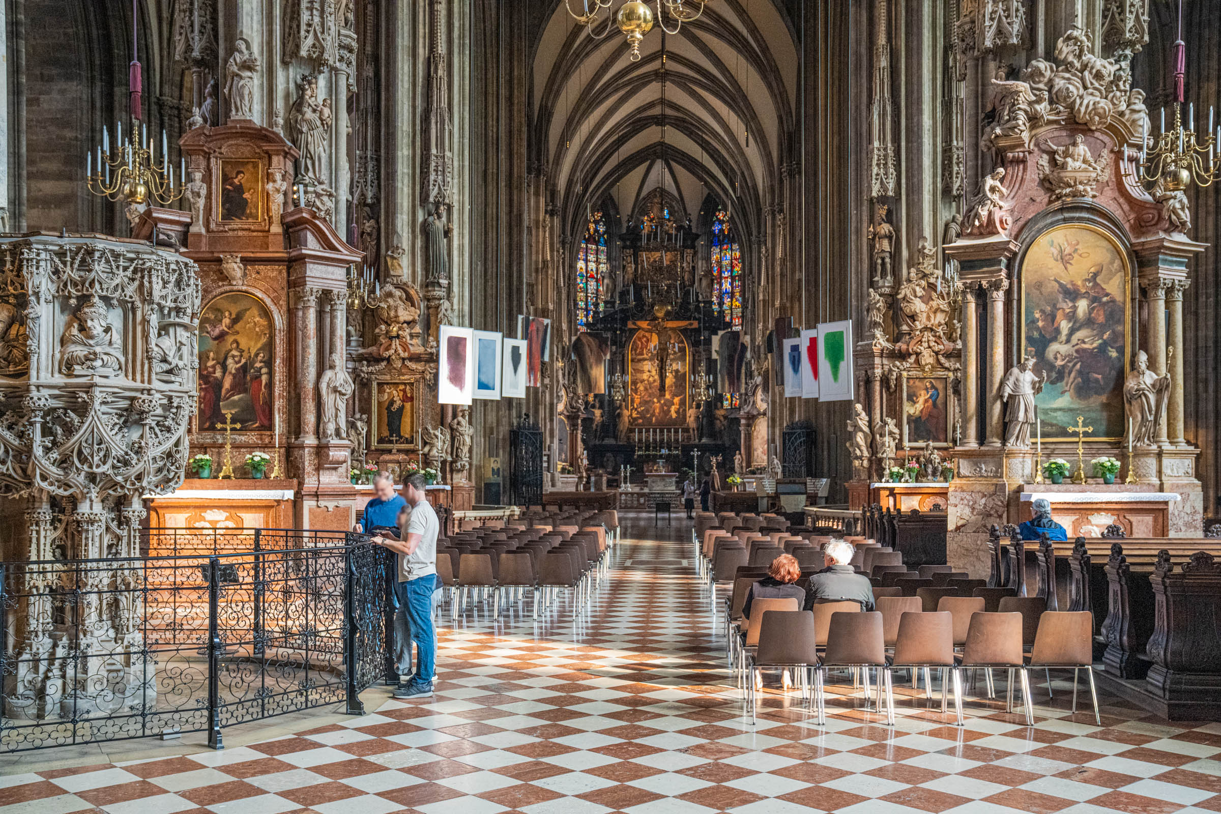 Gothic nave of St. Stephen's Cathedral Vienna with checkered marble floor, stone pulpit and baroque altars
