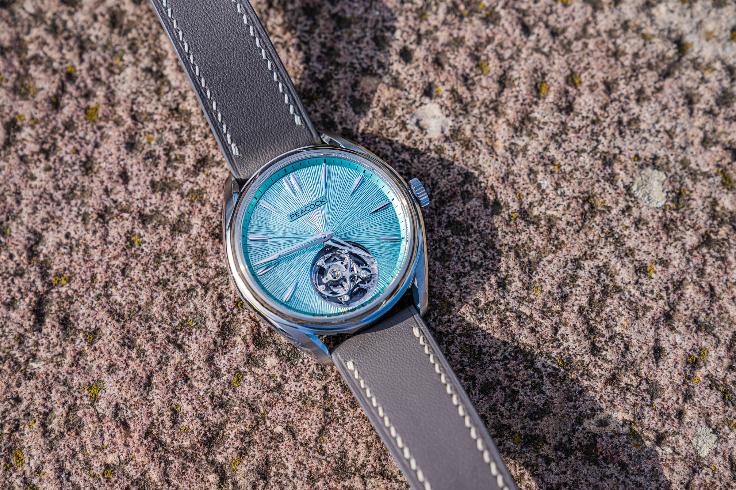 Peacock Divine Craft Tourbillon with grey calfskin strap photographed on stone