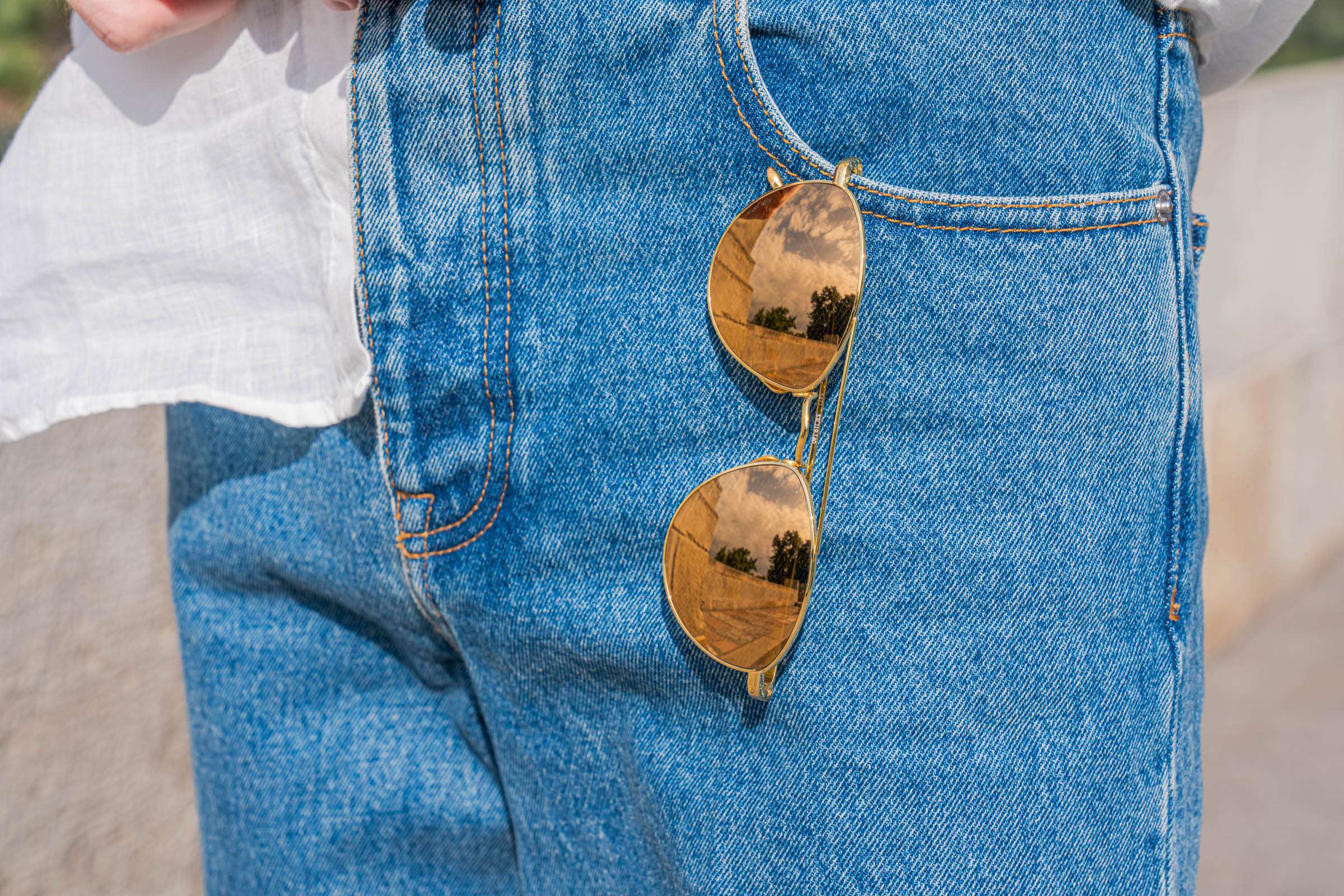 Linda Farrow gold aviators tucked into the front pocket of Valentino jeans, worn by Marko Tadić
